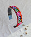 Vibrant Navratri headband featuring colorful embroidered circular patterns in red, green, pink, and purple, displayed on a clear stand.