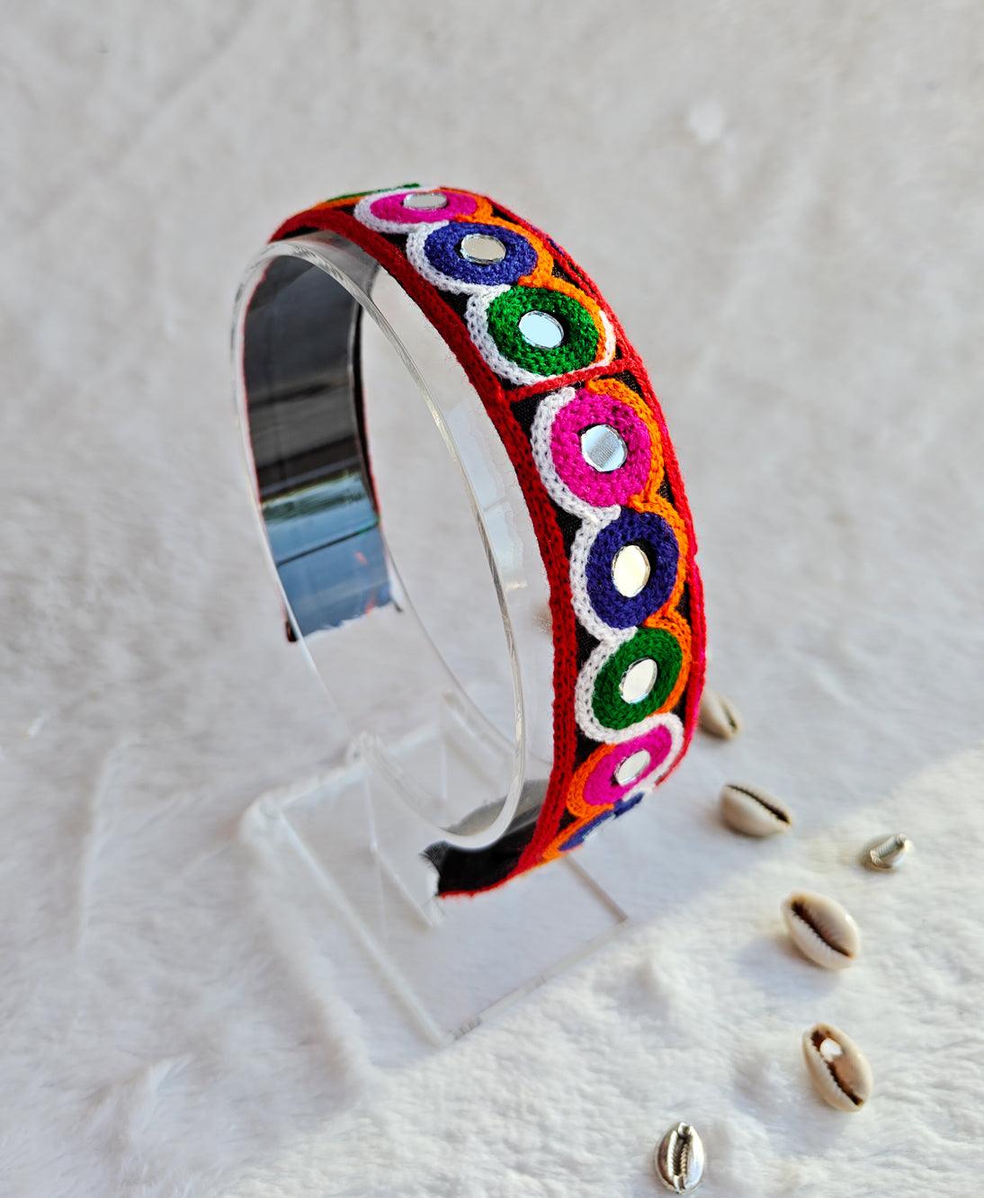 Vibrant Navratri headband featuring colorful embroidered circular patterns in red, green, pink, and purple, displayed on a clear stand. Main image